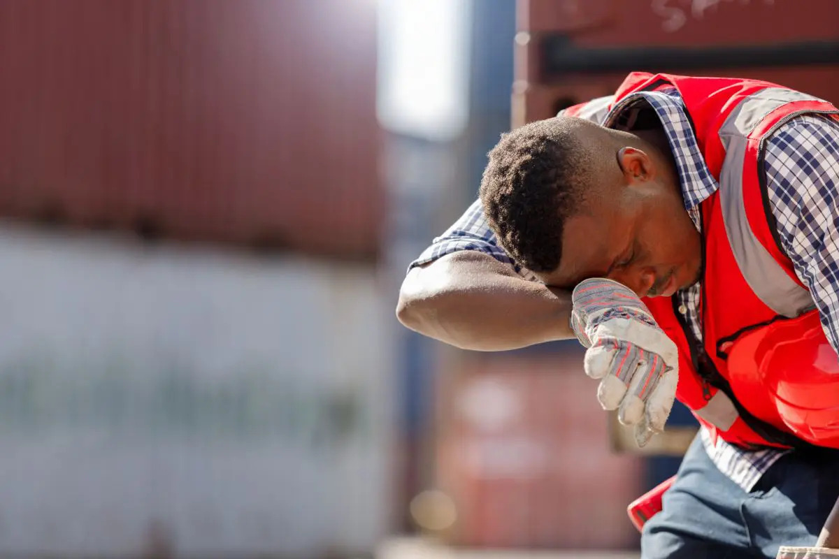 Un lavoratore di cantiere stanco sotto il caldo estivo